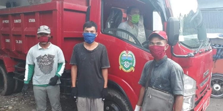 Petugas pengangkut sampah dan supir mengenakan masker