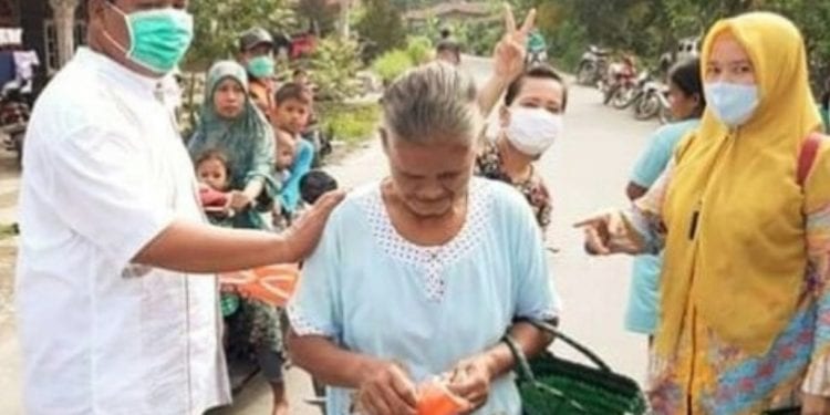 Kades Tanjung Harapan, Rustam Efendi (kiri) saat membagikan masker kepada warga langsung di pasar tradisional.