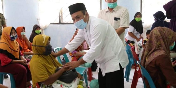 Bupati Labuhanbatu H Andi Suhaimi Dalimunthe ST MT saat memberikan bantuan Sembako kepada warga.