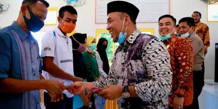 Bupati Labuhanbatu, H Andi Suhaimi Dalimunthe saat menyerahkan BST APBD kepada masyarakat.