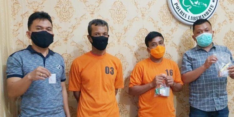 Kedua tersangka beserta barang bukti diapit personil Polisi di Mapolres Labuhanbatu.