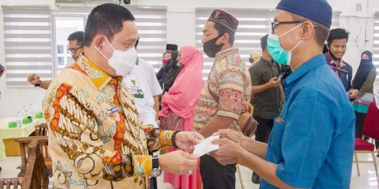 Pjs Bupati Labuhanbatu Drs.H.Mhd Fitryus saat menyerahkan zakat kepada salahseorang mahasiswa.