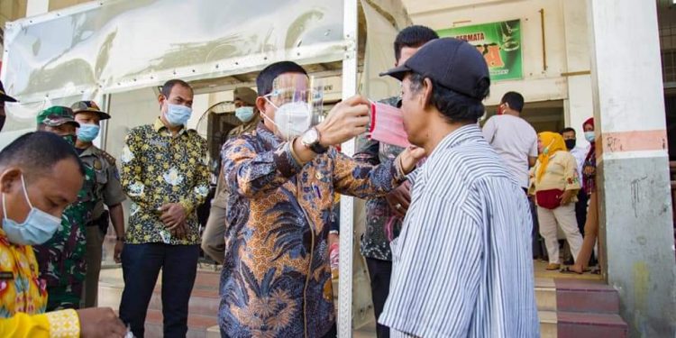 Pjs Bupati Labuhanbatu, Drs H Mhd Fitryus saat memakaikan masker kepada warga di Pasar Gelugur.