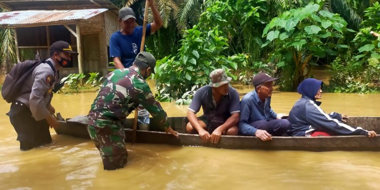 (Richad Silaban/taslabnews) Petugas Polsek Kualuh Hulu dan Koramil 01/AK mengevakuasi warga yang rumahnya terendam banjir