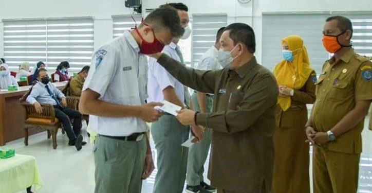 Pjs Bupati Labuhanbatu, Drs H Mhd Fitryus saat memberikan bantuan secara simbolis kepada calon mahasiswa.