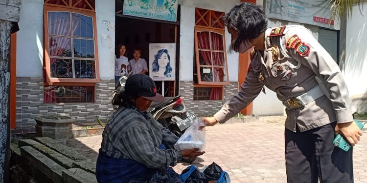 Kasat Lantas Polres Pematangsiantar, AKP Relina Lumban Gaol saat membagikan santap siang kepada warga yang kurang mampu.