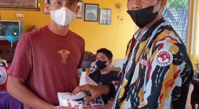 Ketua PKN Labuhanbatu Ricky saat memberikan satu karung beras kepada warga yang mengikuti vaksinasi massal.