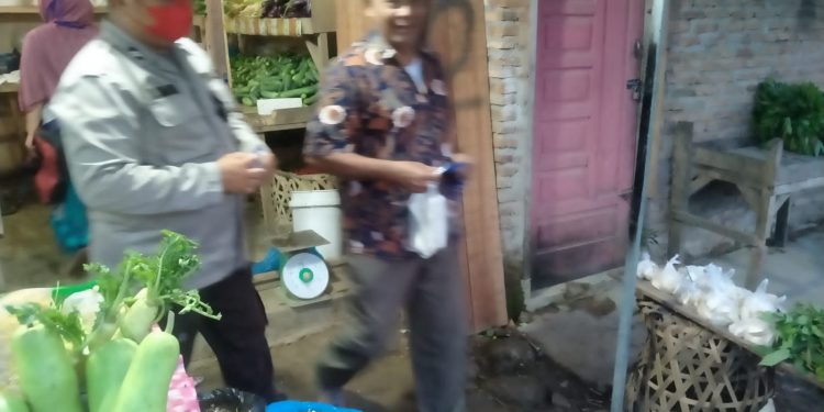 Personel Polsek Bandar Pulau Polres Asahan Bagikan Masker di Pajak Pagi Desa Aek Songsongan