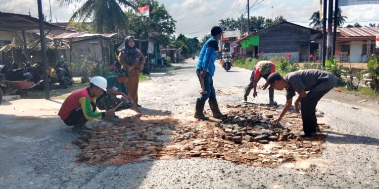 Walaupun belum ada dipedulikan Wakil Rakyat, Warga Desa Meranti gotong eoyong timbun lubang jalan. (foto: edi surya)